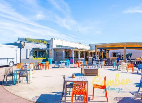 a patio with colorful chairs and tables in front of a building at MP250 Camber Sands Holiday Park in Camber