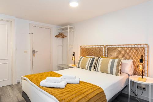 a bedroom with a bed with two towels on it at BNBHolder Calm Duplex Retiro Free Parking in Madrid