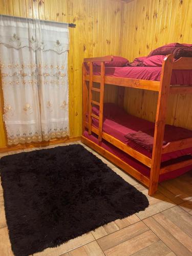 1 dormitorio con 2 literas y alfombra negra en Cabañas “La India” en Jardín América
