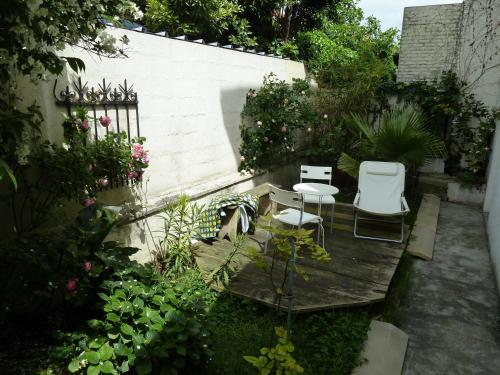 einen Garten mit 2 Stühlen und einem Holztisch in der Unterkunft Maison des Peupliers in Bondy
