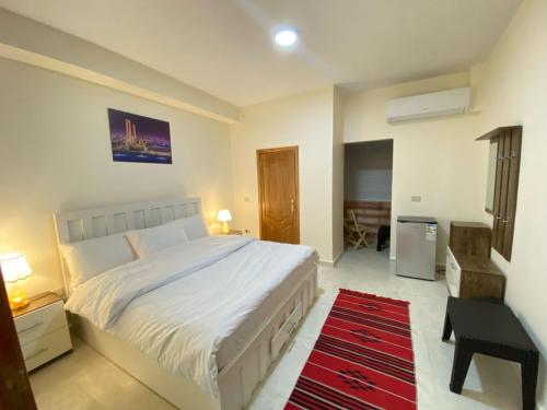 Un dormitorio con una gran cama blanca y una alfombra roja en Petra rose city en Wadi Musa