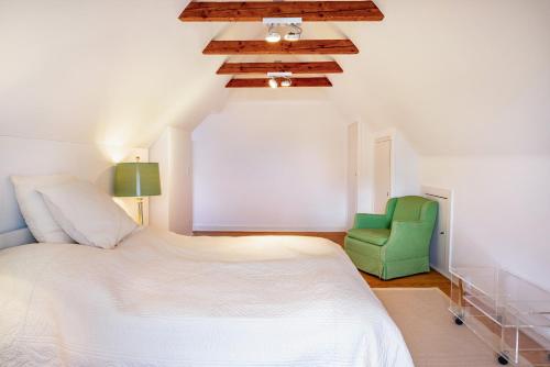a bedroom with a bed and a green chair at Buchenhof in Delingsdorf