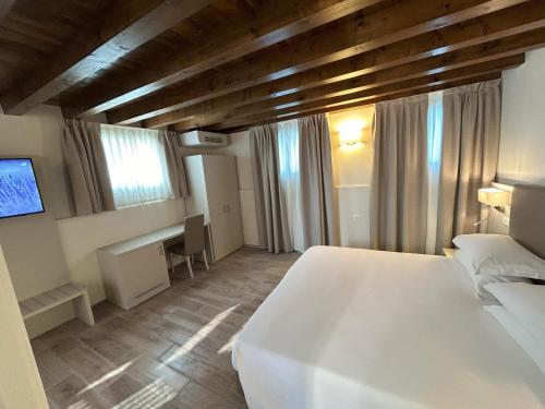 a bedroom with a white bed and a desk at La Casetta in Sarmeola