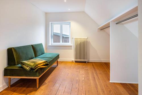a green couch in a room with a window at Buchenhof in Delingsdorf