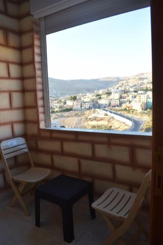 Petra rose city في وادي موسى: غرفة مع نافذة بها كرسيين وطاولة