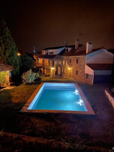 a swimming pool in front of a house at night at La coruña Sas playa y golf in Paderne