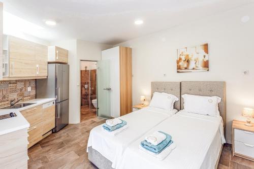 a bedroom with a white bed and a kitchen at A&A Luxury Beach Villas in Nikiti