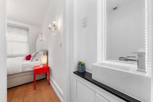 a white bedroom with a bed and a sink at 1BR Harrods Hydepark Knightsbridge KB91 in London
