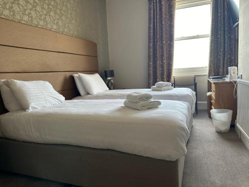 a hotel room with two beds with towels on them at Merrion Hotel in Llandudno