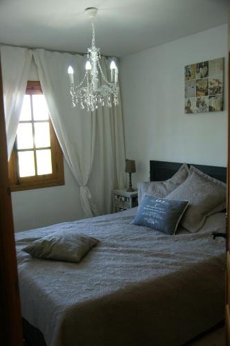 a bedroom with a bed with a chandelier and a window at Residence Los Jardines in Alcossebre