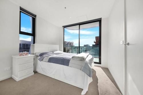 ein weißes Schlafzimmer mit einem Bett und großen Fenstern in der Unterkunft Top Location 2 BR Apt Amazing View & Free parking in Melbourne