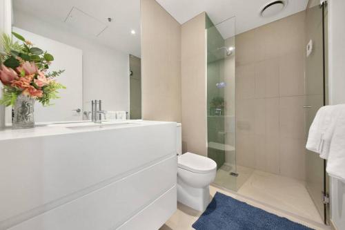 Baño blanco con aseo y lavamanos en Top Location 2 BR Apt Amazing View & Free parking, en Melbourne