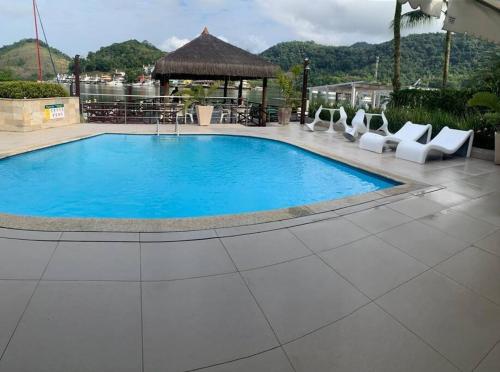 una gran piscina rodeada de tumbonas blancas. en Casa com pier e área gourmet., en Angra dos Reis