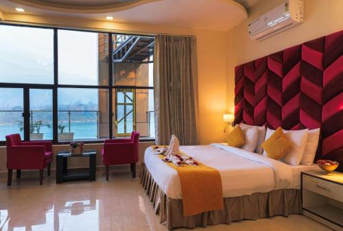 リシケーシュにあるThe Neeraj Naturecure On Gangaのベッドと大きな窓が備わるホテルルームです。