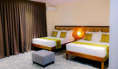 a hotel room with two beds and a stool at Maxi Hotel and Event Center in Tagbilaran City