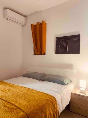 een slaapkamer met een bed met een gele deken en een raam bij Centeraly Located Cozy Apartment in Gzira in Il- Gżira