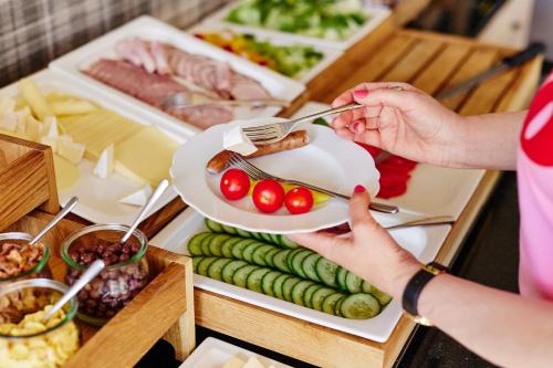 a woman holding a plate of food with tomatoes and cucumbers at Pokoje Kameralne in Konopnica