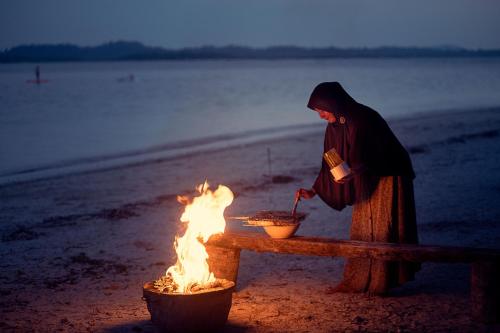 a woman standing next to a fire on the beach at Tailana Island Pulau Banyak in Alaban
