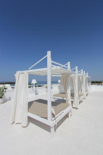 a row of white lounge chairs on a roof at Hotel Paladini in Porto Cesareo