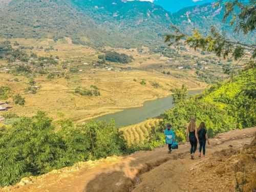 three people walking down a dirt path overlooking a river at Duy Tuyen Ba Be Homestay in Bak Kan