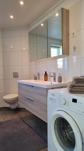 uma casa de banho com uma máquina de lavar roupa e um lavatório em Haramsøy Holiday Apartment- Island Life North em Haram