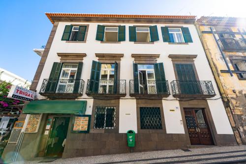 un alto edificio bianco con finestre con persiane verdi di Alojamento Local Trigal a Funchal