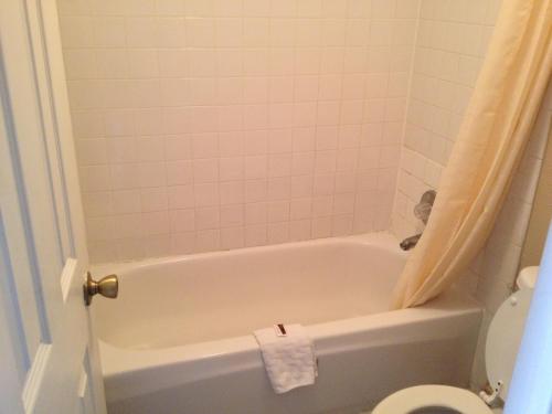 a bathroom with a white tub and a toilet at Austin Motor Inn in Austin