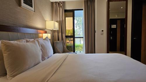 Imperial Plaza Hotel & Resort Juba في جوبا: غرفة نوم بسرير ابيض كبير ونافذة