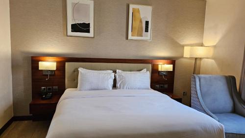 a bedroom with a large bed and a blue chair at Imperial Plaza Hotel, Juba in Juba
