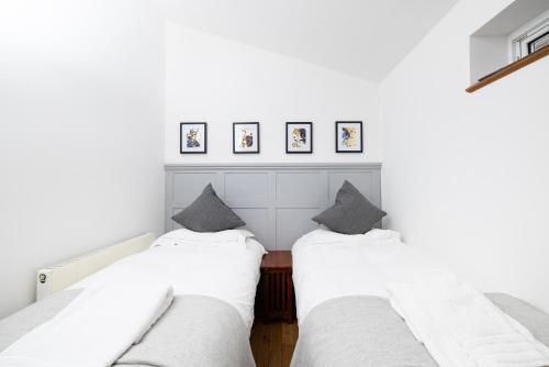 two beds in a room with white walls at The Chalet - Stunning apartment in London