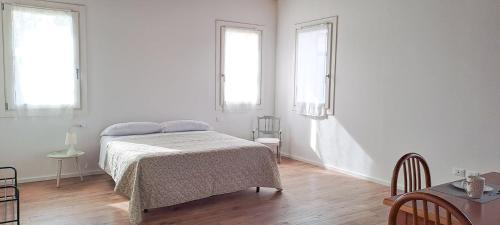 a white bedroom with a bed and two windows at Casa Toe' Quinto in Quinto di Treviso
