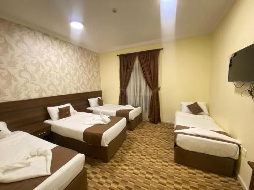 una camera d'albergo con tre letti e una televisione di مرجان أنوار الروضة a La Mecca
