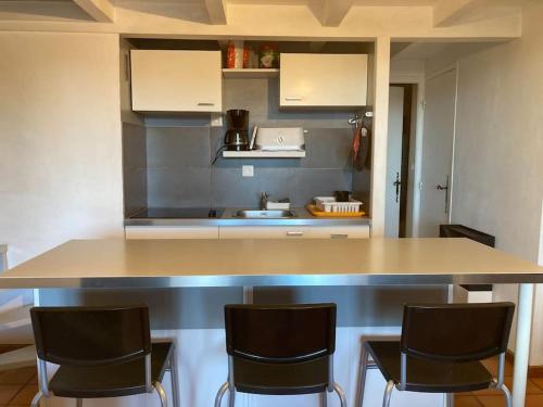 a kitchen with a counter with three bar chairs at Joli appartement et terrasse vue sur les dentelles in Sablet