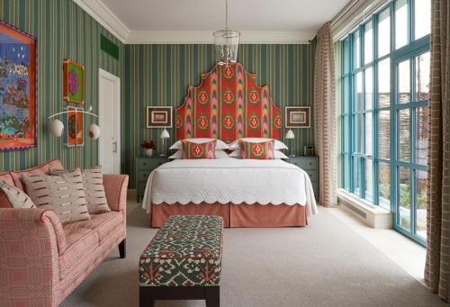 a bedroom with a bed with a red headboard and a couch at Warren Street Hotel in New York