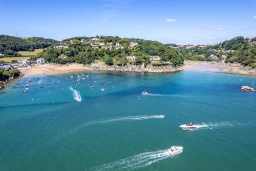 a group of boats in the water near a beach at Harbour Beach Club, Hotel & Spa in Salcombe