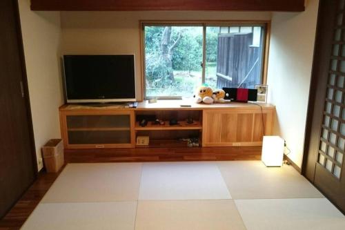 a living room with a flat screen tv on a entertainment center at countryside stay ゲストハウスもらいもん in Kanaya