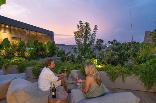a man and woman sitting on a patio with wine bottles at Sin Nombre Bali - Sauna, Ice Bath & Roof Terrace in Canggu