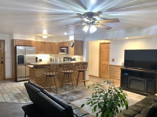 a living room with a ceiling fan and a kitchen at Bridge Inn Tomahawk - Suite 101, Kitchen, 1 Kind Size Bed, 2 Futons, Walkout, River View in Tomahawk