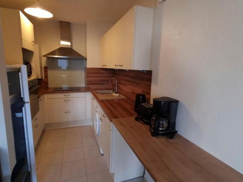 une cuisine avec des armoires blanches et un comptoir en bois dans l'établissement Appartement T2 Rez-de-Jardin à 50m de la Plage à Courseulles-sur-Mer - FR-1-746-16, à Courseulles-sur-Mer