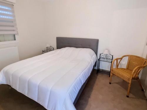 une chambre avec un lit blanc et une chaise dans l'établissement Appartement T2 Rez-de-Jardin à 50m de la Plage à Courseulles-sur-Mer - FR-1-746-16, à Courseulles-sur-Mer