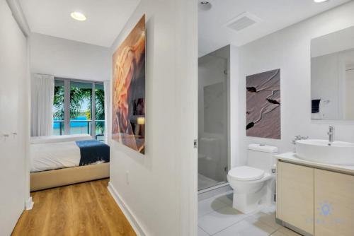 a white bathroom with a bed and a toilet and a sink at Modern Resort - Apartment with Balcony, Pool and Gym in Hallandale Beach