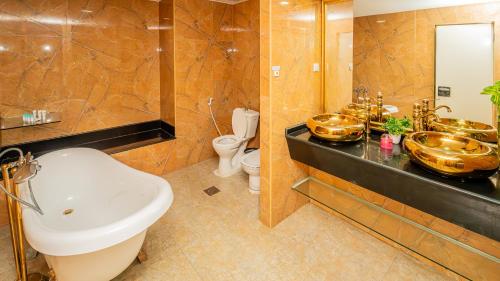a bathroom with a sink and two mirrors and a toilet at Al Dar Inn Hotel Apartment in Ras al Khaimah