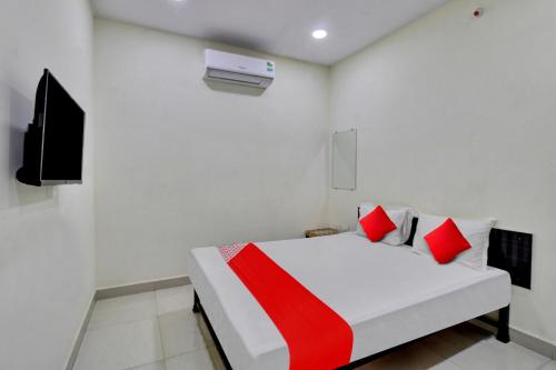 a white room with a bed with red pillows at OYO Flagship Hotel Green Farm in Nagpur