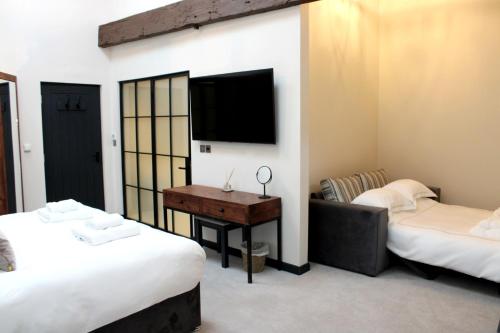 a room with two beds and a desk and a tv at The Merchant's Yard in Tideswell