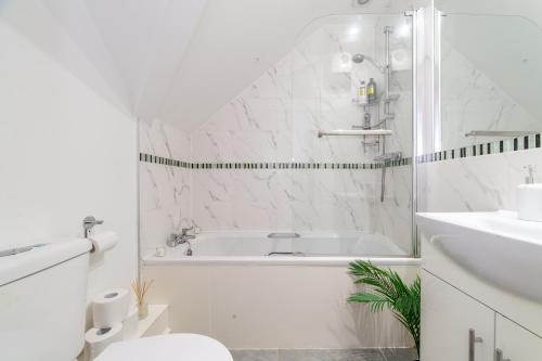 a white bathroom with a tub and a sink at Great 1 bedroom In Hounslow with free parking in Abbey Wood