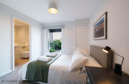 a bedroom with a bed with a desk and a window at Rampart View in Gosport