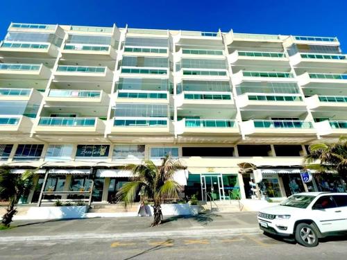 un coche blanco estacionado frente a un gran edificio en Recanto do Pôr do Sol, en Arraial do Cabo