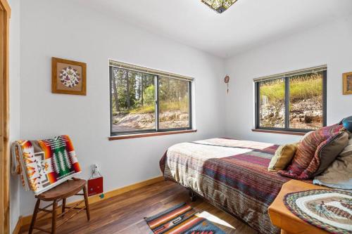 ein Schlafzimmer mit einem Bett und einem Stuhl und Fenstern in der Unterkunft Timberline Escape Overlook in Spearfish