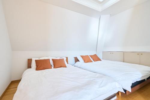 two beds in a bedroom with white sheets and orange pillows at L-Large 3Bedroom Luxury Condo, 140sqm Max 19 PPL, 7mins walk to station, Elevator,QuiteArea in Tokyo