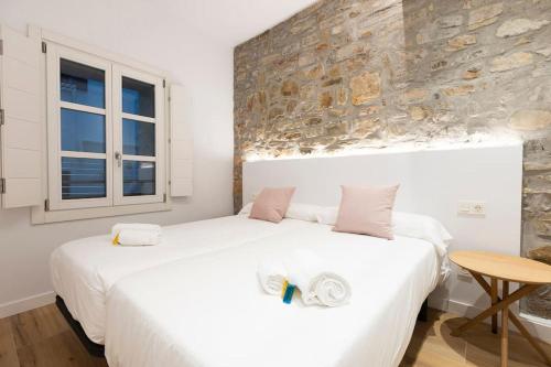 een slaapkamer met 2 bedden en een stenen muur bij Alde-zahar. Basquenjoy in Hondarribia